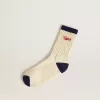 Crèmekleurige geribde sokken met marineblauwe details en rood logo
