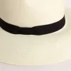 Gouden fedora hoed van wit stro met zwart lint en maritieme print onder de rand.