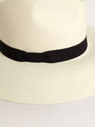 Gouden fedora hoed van wit stro met zwart lint en maritieme print onder de rand.
