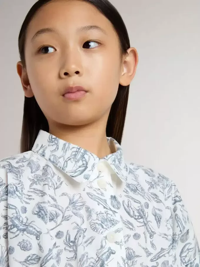 Meisjesshirtjurk van wit katoenen canvas met een blauwe nautische print en witte biezen.