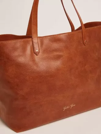 Pasadena-tas in glanzend, gehamerd leer in tan-kleur met gouden logo op de voorkant