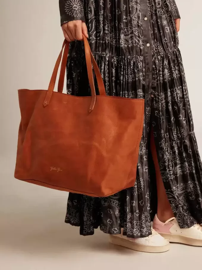 Pasadena-tas in glanzend, gehamerd leer in tan-kleur met gouden logo op de voorkant