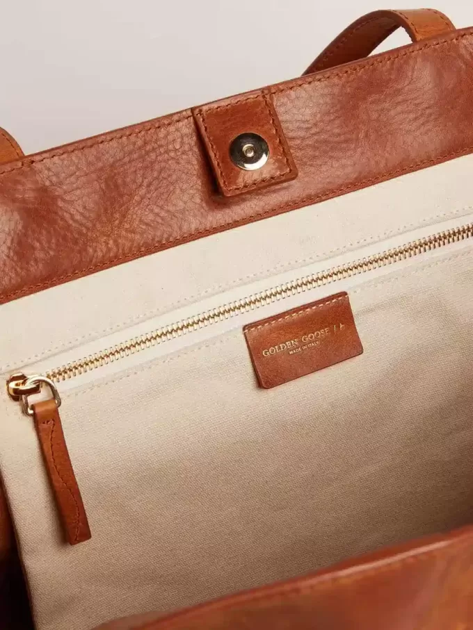 Pasadena-tas in glanzend, gehamerd leer in tan-kleur met gouden logo op de voorkant