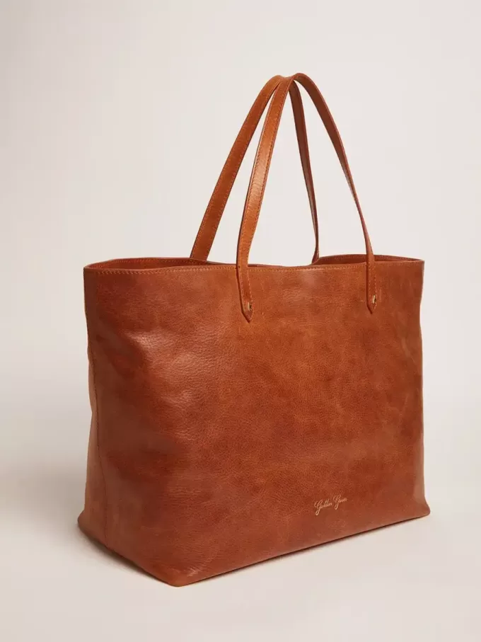 Pasadena-tas in glanzend, gehamerd leer in tan-kleur met gouden logo op de voorkant