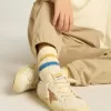 Witte kindersokken met distressed details en tweekleurige felblauwe en mosterdkleurige strepen.